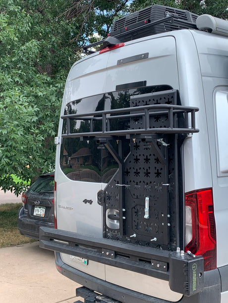 Rear of a silver Sprinter 4x4 camper van, ready for RV rental adventures with a custom cargo rack and roof AC.