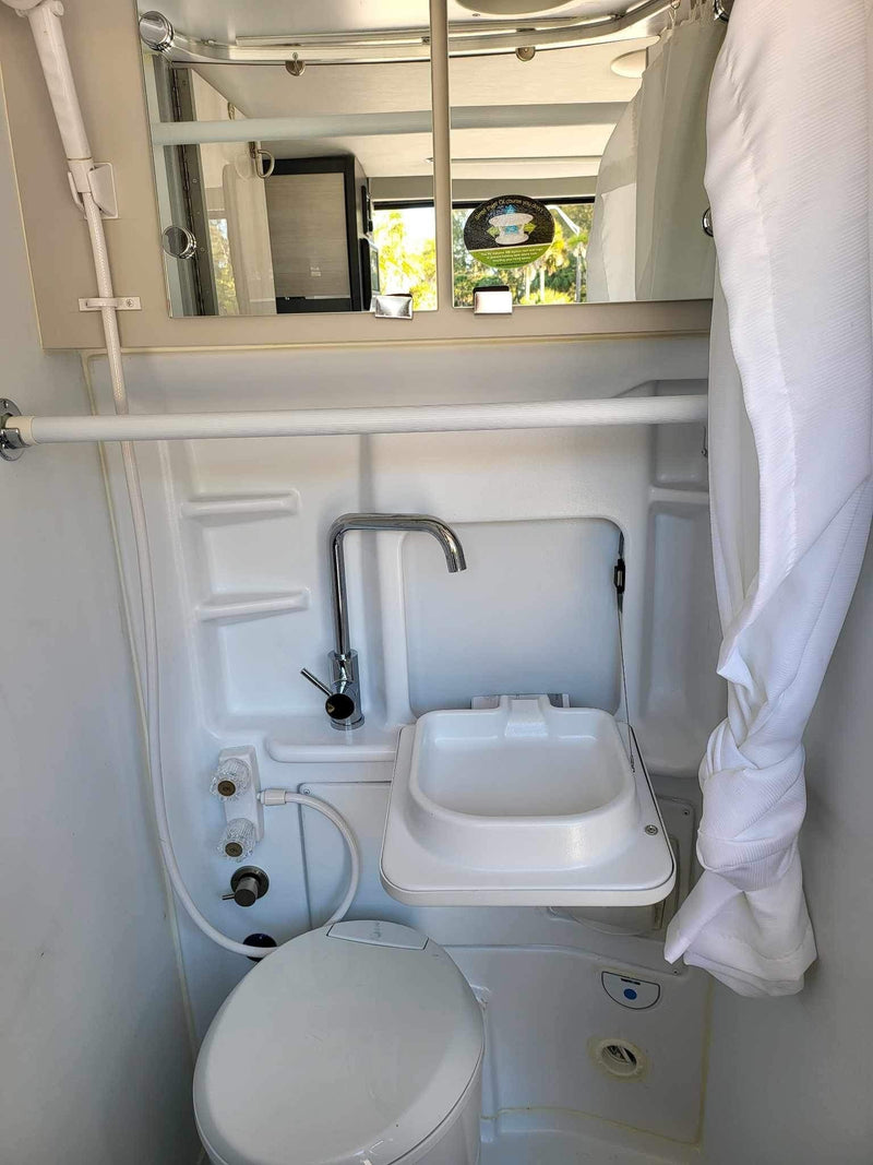 This RV rental features a compact wet bath with a toilet, sink, and shower, maximizing space for travelers. — photo 11