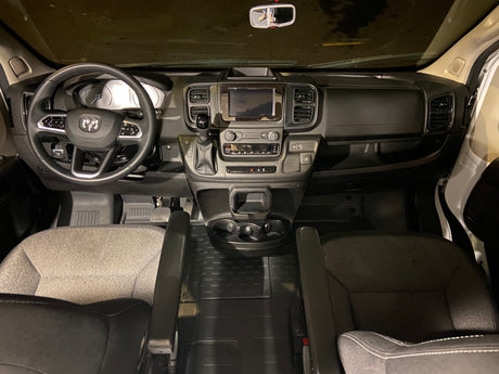 RV rental van's driver cockpit: modern dashboard, steering wheel, infotainment screen, gear shift, and front seats.