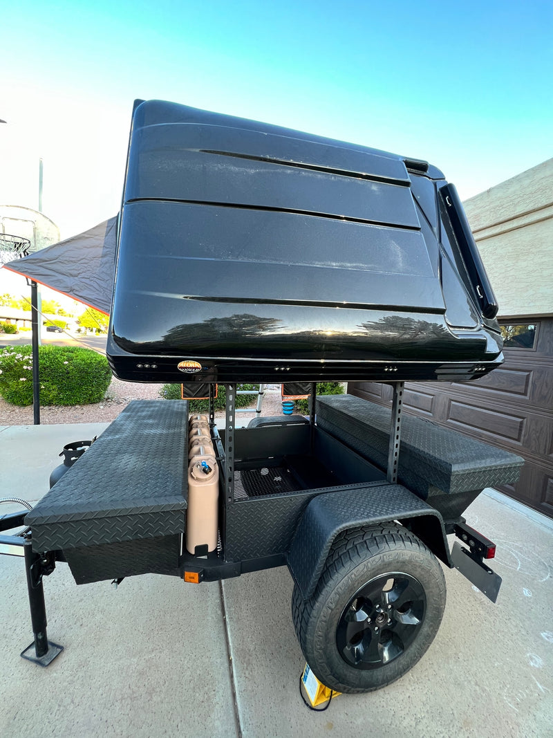 A black off-road trailer with a hard-shell rooftop tent, featuring storage and utilities for a versatile RV rental camping experience. — photo 15