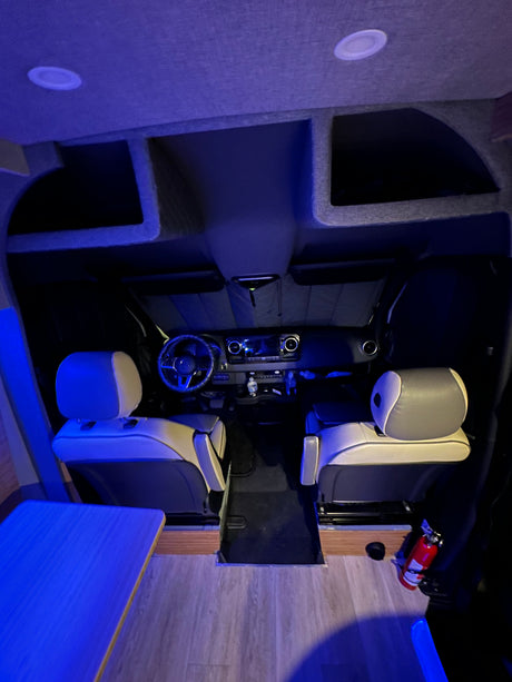 Inside a modern RV rental: comfortable front seats, a detailed dashboard, and serene blue ambient lighting for travel.