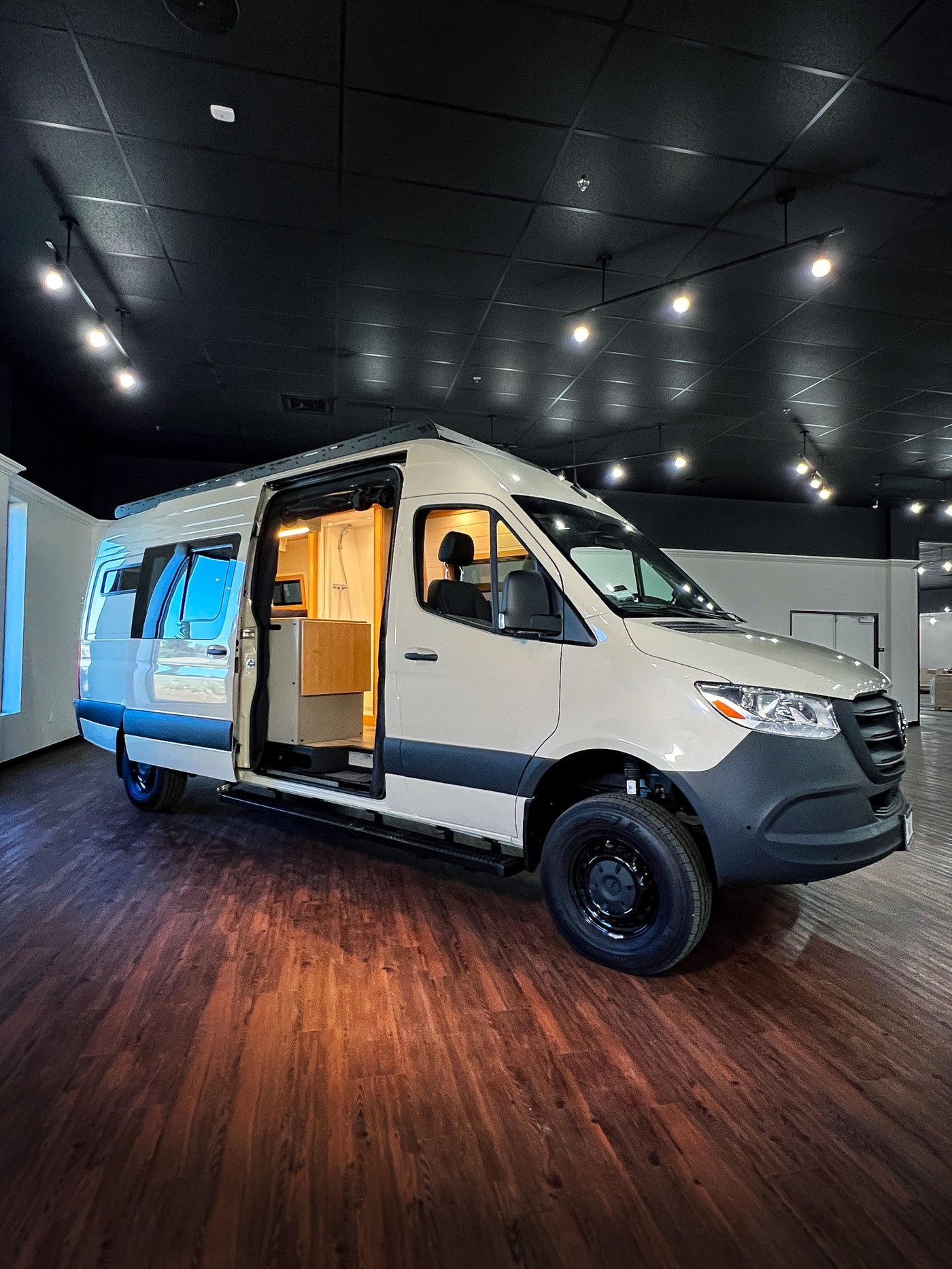Ready for adventure! This modern beige camper van with an open side door reveals an interior shower — photo 1