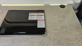 A Dometic RV cooktop with prominent safety warnings and a wireless charging pad, common in an RV rental.