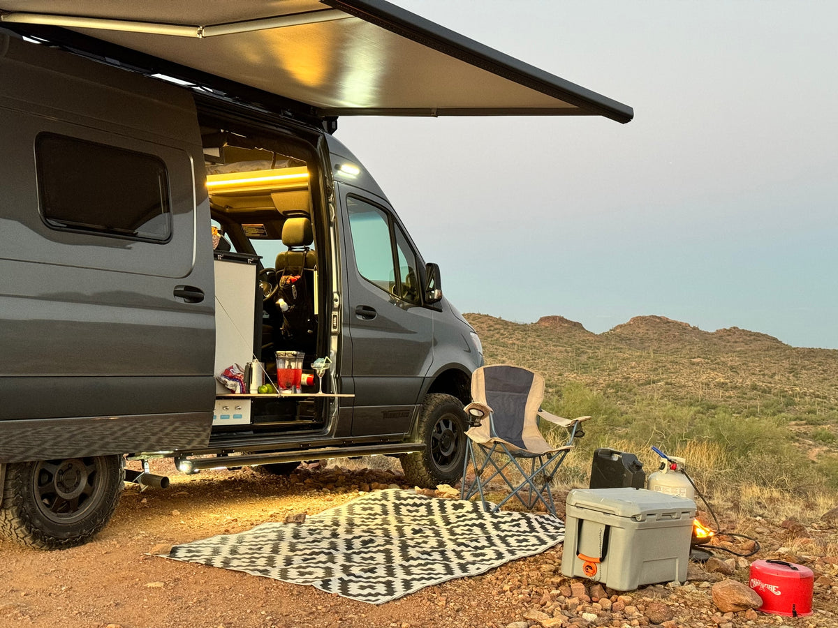 Enjoy the desert sunset with this cozy rv rental setup. Camper van with open door