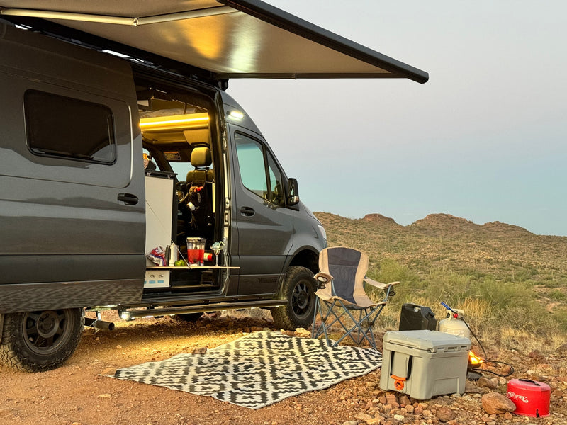 Enjoy the desert sunset with this cozy rv rental setup. Camper van with open door — photo 1