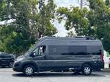 A white dog peeks from an **RV rental** van (Entegra Ethos), parked outdoors.