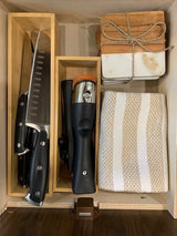 RV rental kitchen drawer with organized knives, wine opener, coasters, and towel. Compact storage for cooking essentials.