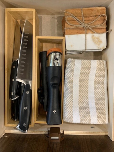 RV rental kitchen drawer with organized knives, wine opener, coasters, and towel. Compact storage for cooking essentials.