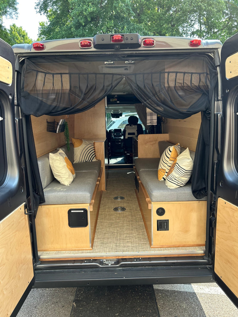 Inside a modern RV rental: wood-paneled interior with comfy benches, power outlets, and a bug screen at the rear. Ready for adventure. — photo 10