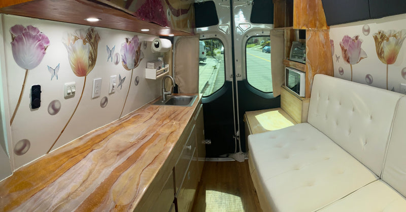 Spacious RV rental interior. Features a custom kitchen with unique gold-swirl counter, sink, appliances, and cozy sofa. — photo 6