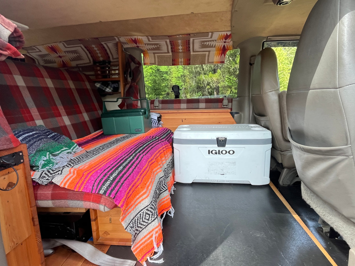 Explore this cozy RV rental interior with a built-in bed, colorful blankets, Stanley and Igloo coolers, ready for mobile living. — photo 7