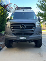 Front of a rugged grey Mercedes Sprinter rv rental van, parked by a hoop, ready for adventure.