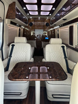 Luxury RV rental interior with plush white seating, wood table & elegant paneling.