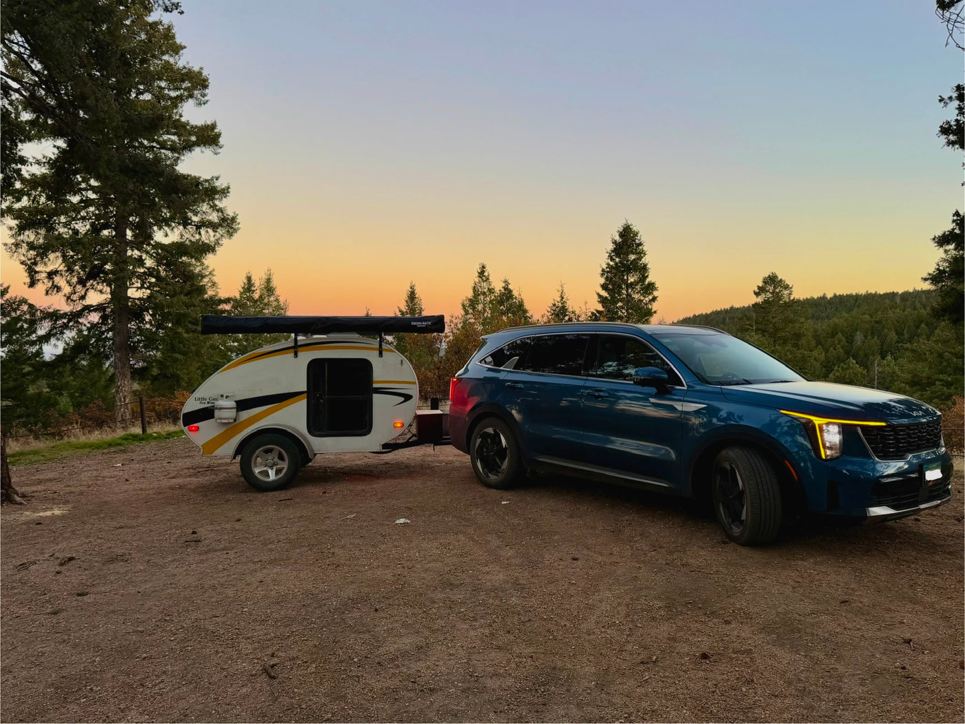 Serene dusk scene: Blue SUV towing a 'Little Guy' teardrop RV rental, ready for a forest camping getaway. — photo 2