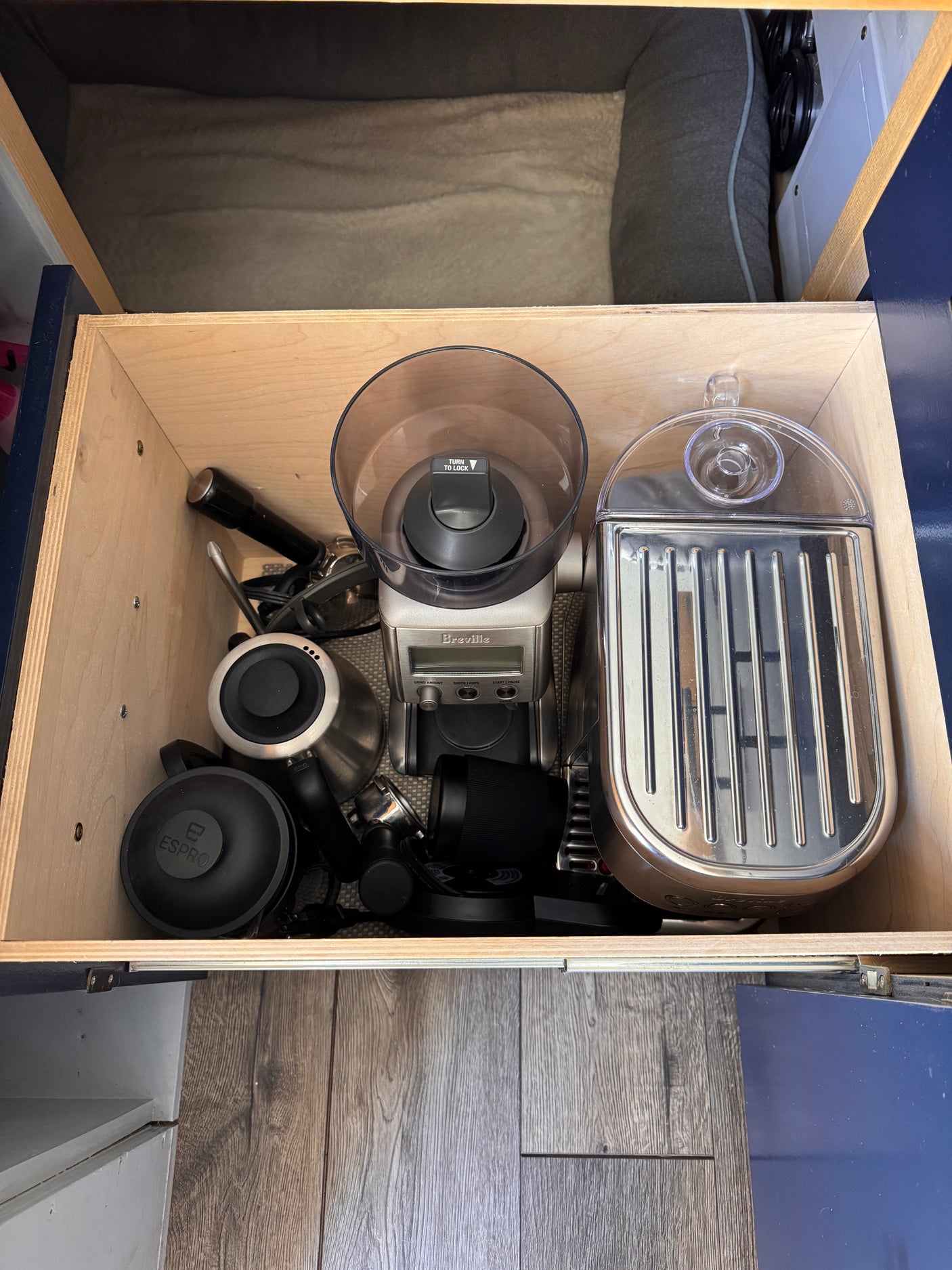 Compact coffee setup in an RV rental drawer, featuring a Breville grinder, kettle, and espresso machine for mobile brewing.