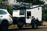 RV rental: A silver SUV tows a white and black TigerMoth off-road camper trailer with a Thule Tepui rooftop tent.