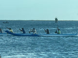 Paddlers in an outrigger canoe glide on the water. Explore nature's beauty, maybe even with an RV rental.