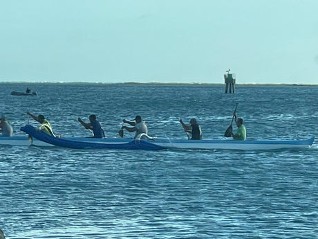 Paddlers in an outrigger canoe glide on the water. Explore nature's beauty, maybe even with an RV rental.