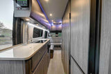Modern rv rental interior: kitchen with smart panel, sleek overhead storage, and cozy rear seating, ideal for travel.