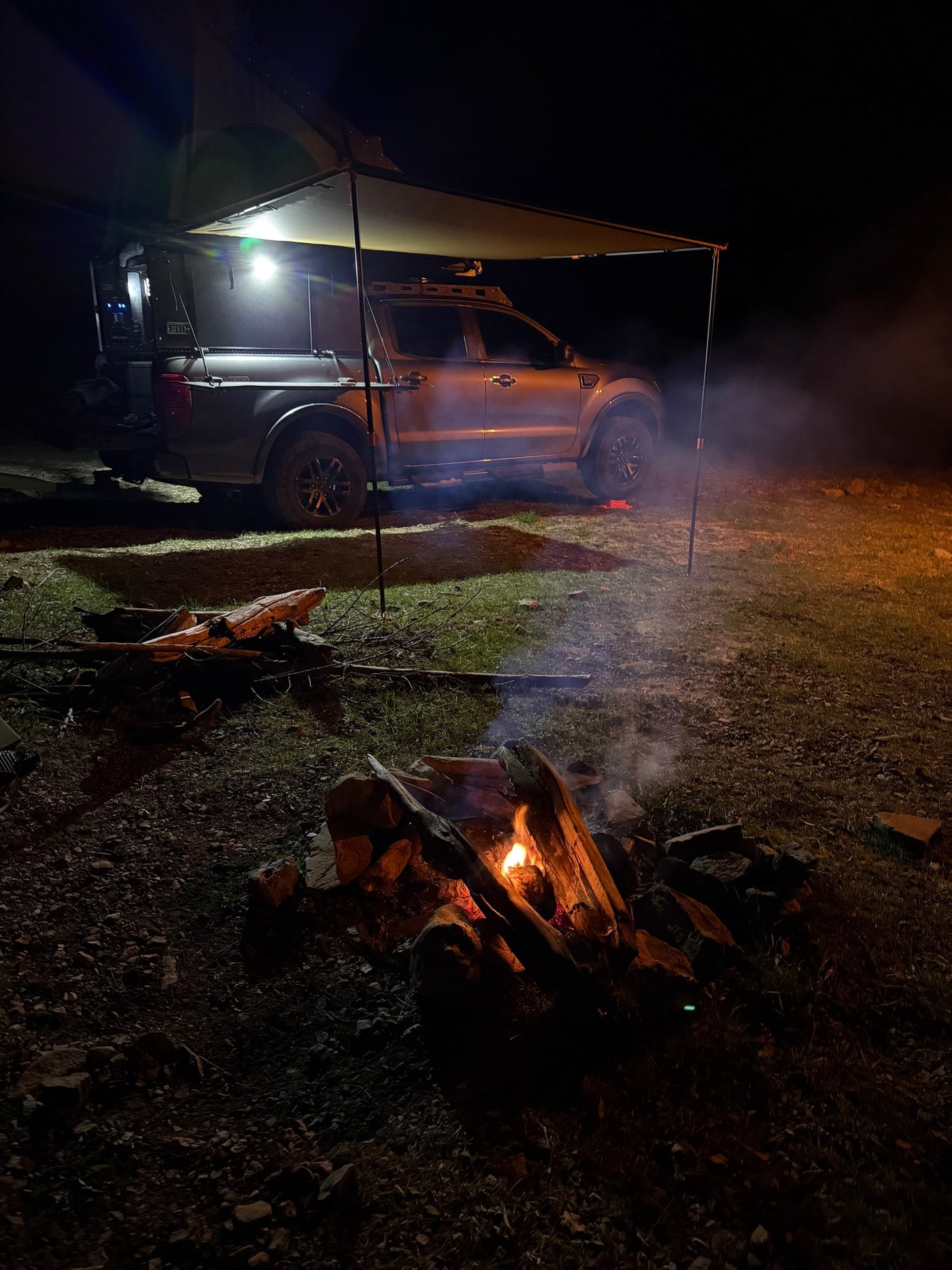 Night camping: A truck with an awning & bright lights next to a cozy campfire. Experience overland adventure with an RV rental! — photo 13
