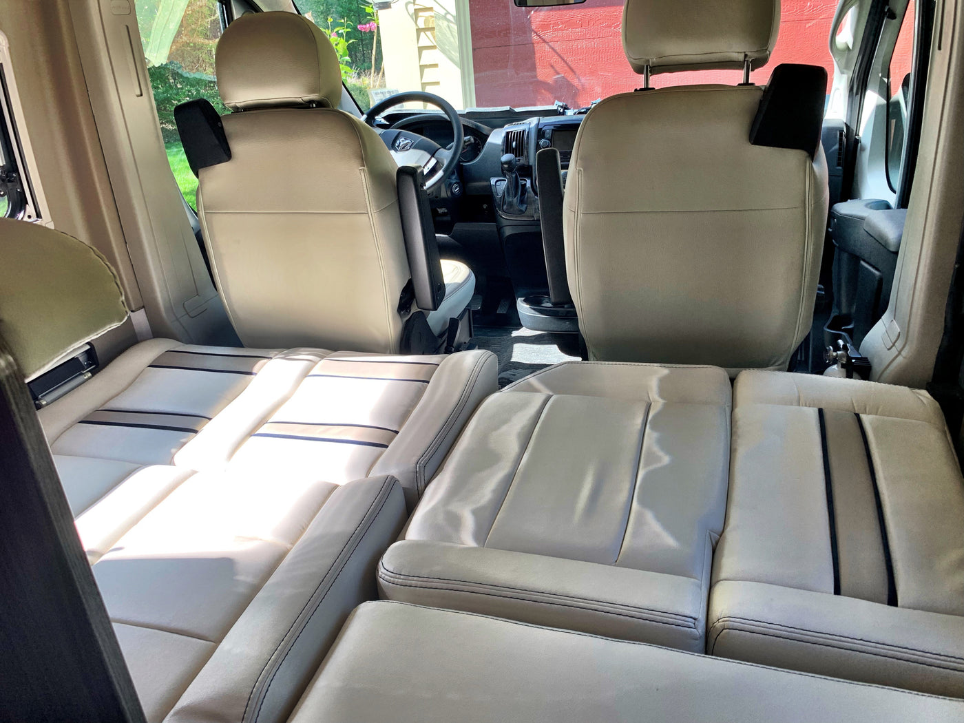 RV rental interior: View of driver/passenger seats and modular seating that converts to a bed in a light-colored camper van. — photo 12