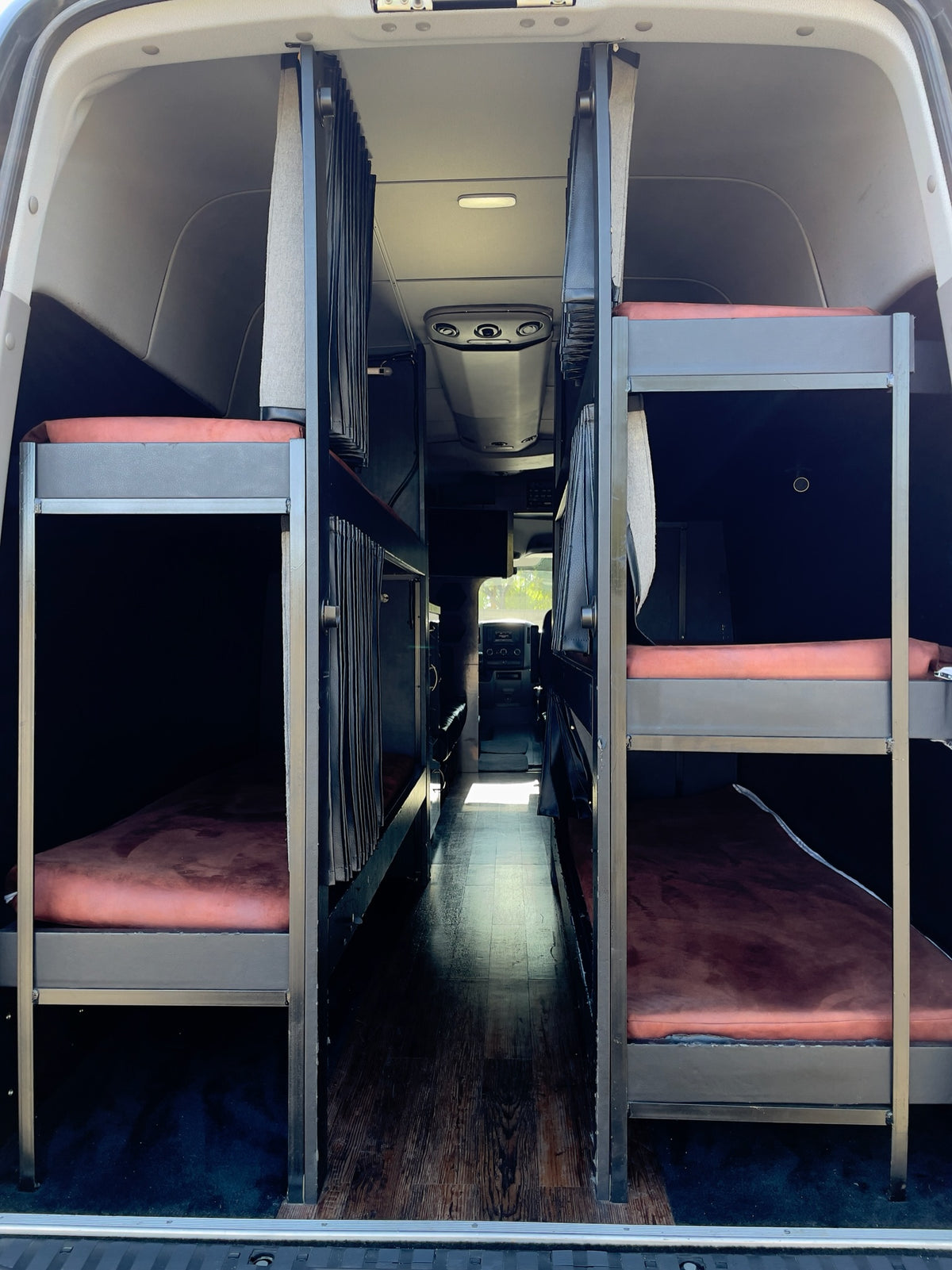 RV rental's interior: two rows of bunk beds with brown mattresses create a narrow central aisle inside this van. — photo 7