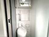 Essential RV rental amenities: a compact wet bath with toilet, shower, and mirror, designed for travel convenience.