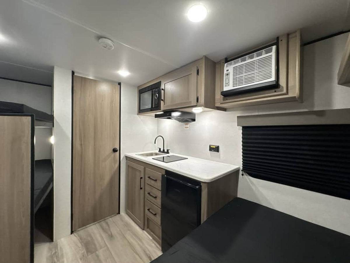  awaits adventure outside an RV store.|RV rental interior: view of bunk beds — photo 8