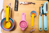 RV rental kitchen essentials: colorful measuring cups/spoons, can opener, corkscrew, egg separator, and lighter.