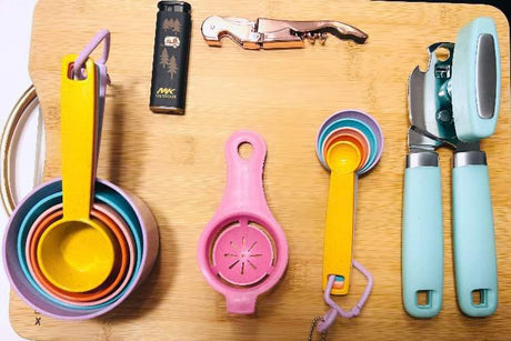 RV rental kitchen essentials: colorful measuring cups/spoons, can opener, corkscrew, egg separator, and lighter.