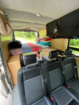 Inside this RV rental, a cozy camper van conversion with a bed, compact kitchen, and passenger seats for adventurous trips.