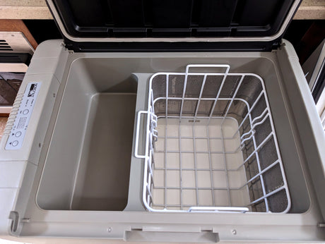 Interior of an open Norcold portable refrigerator/cooler, showing two compartments and a wire basket, perfect for RV rental use.