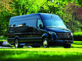 Dark Mercedes-Benz Sprinter van for RV rental, parked on green grass with trees. Ideal for luxury travel & adventure.