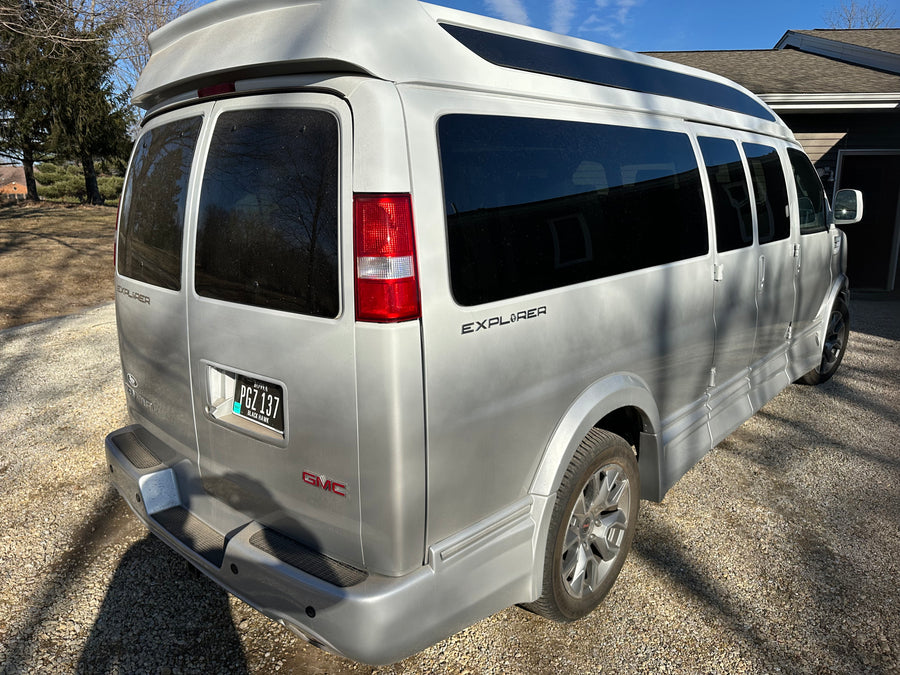 Silver GMC Explorer conversion van, an RV rental. Parked on gravel, ideal for your travels.