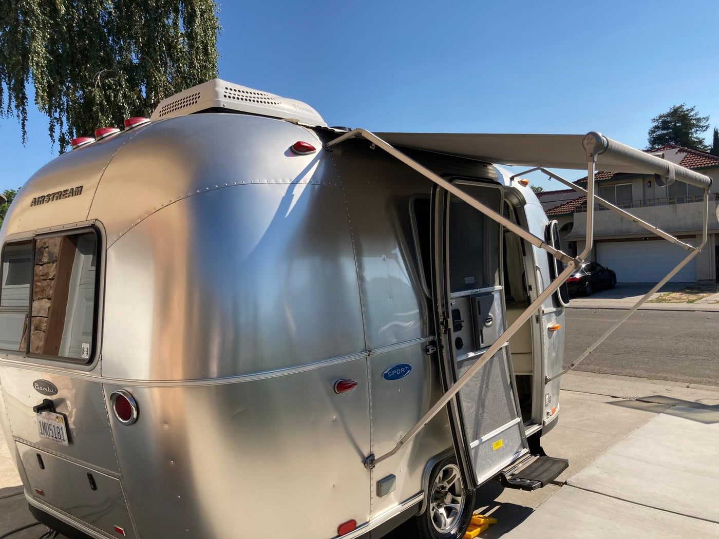  sits parked outdoors among trees.|This RV rental features a compact kitchenette with a sink — photo 3