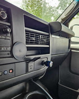 RV rental van interior, focusing on the dashboard. Custom-installed AC power outlet and 12V USB charger are visible.