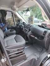Inside an RV rental van, showcasing the grey/black front seats, dashboard, and functional cabin from the passenger's side door.