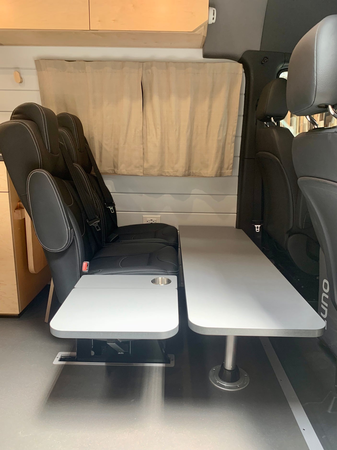 RV rental interior features black modular seating and light gray tables, creating a versatile living space.