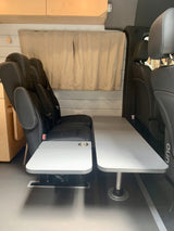 RV rental interior features black modular seating and light gray tables, creating a versatile living space.