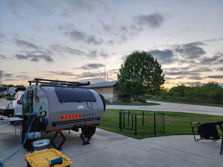 RV rental: A Modern Buggy teardrop trailer with solar panels is set up at a campsite with a pet pen.