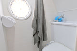 This RV rental features a well-equipped compact bathroom with a porthole window, shower/faucet, and toilet.
