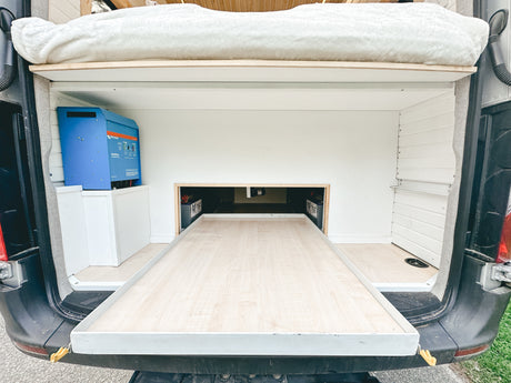 RV rental: Camper van rear with pull-out bed/storage, a blue Victron inverter, and power system setup.
