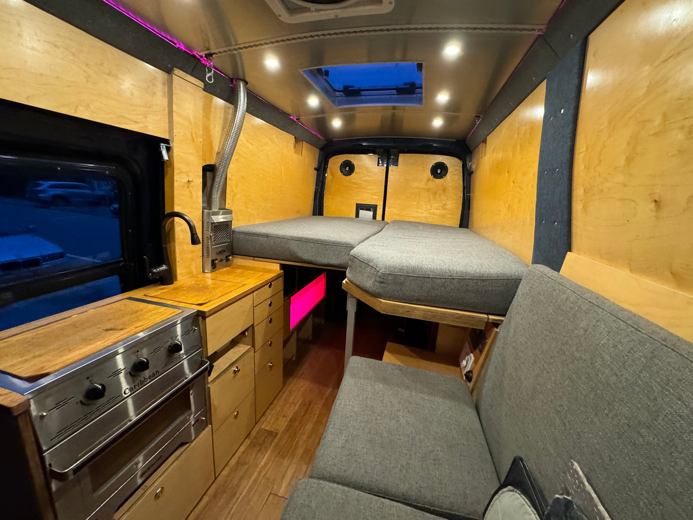Cozy RV rental interior with a built-in kitchen, comfortable bed, and unique lighting. Perfect for adventures.