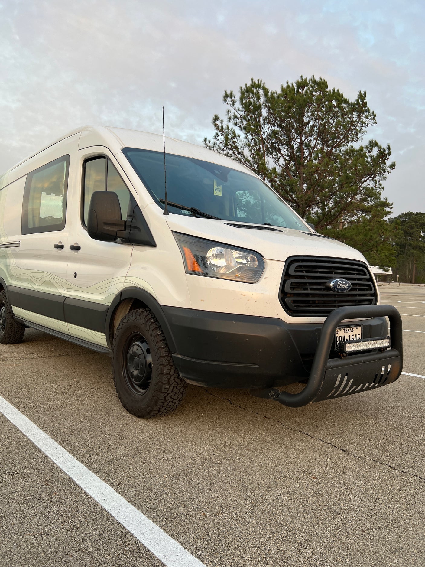 White Ford Transit adventure van with off-road tires and bull bar. Ideal for your next RV rental and exploring Texas.