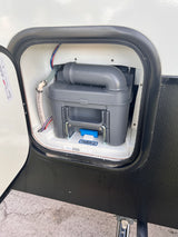 An open exterior compartment on an RV rental reveals its removable waste cassette tank for sanitary maintenance.