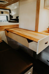 RV rental: A clever light wood pull-out desk with an open storage drawer and cozy bench seating maximizes this camper's space.