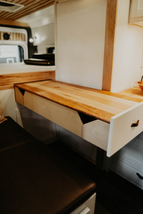 RV rental: A clever light wood pull-out desk with an open storage drawer and cozy bench seating maximizes this camper's space.