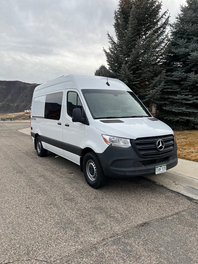 White Mercedes-Benz Sprinter van, a GEOTREK rv rental, parked on a street with a mountainous background. — photo 2