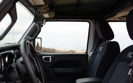 SUV interior: steering wheel, seats (RC logo), person in side mirror. Outside, a landscape. Great vehicle for your RV rental adventures.