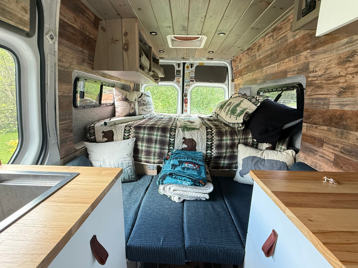 Cozy rv rental interior: wood-paneled walls, comfortable bed, compact kitchen, ideal for a scenic getaway. — photo 11